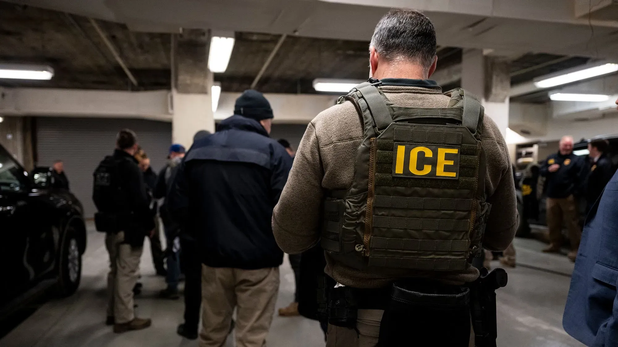 وكلاء الهجرة يرتدون زيهم الرسمي، يتجمعون في موقف سيارات، استعدادًا لتنفيذ عمليات ترحيل الأطفال المهاجرين غير المصحوبين بذويهم.