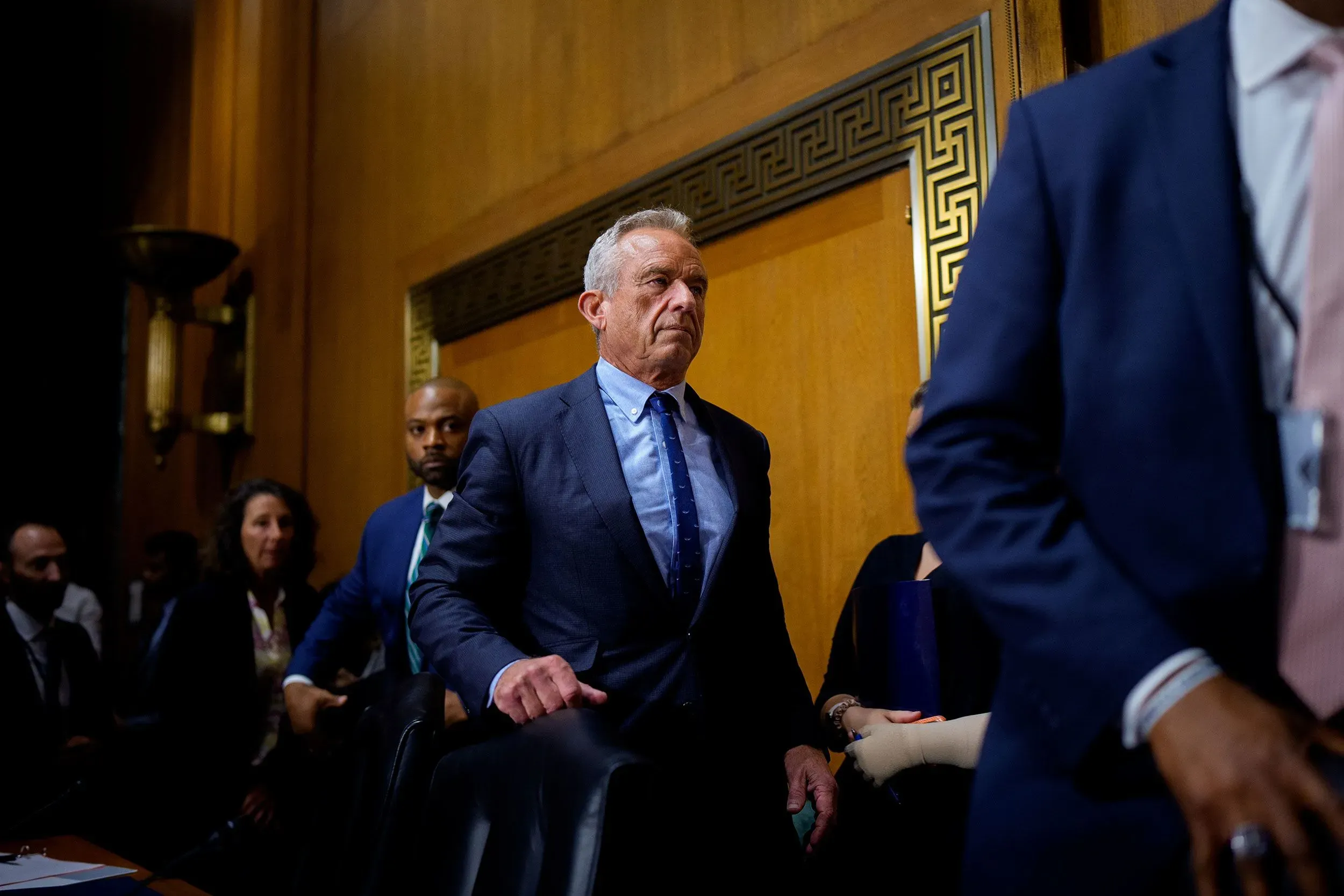 وزير الصحة الأمريكي روبرت ف. كينيدي جونيور يتحدث في جلسة رسمية، مع خلفية تضم موظفين آخرين، معبرًا عن آرائه حول وكالات الصحة العامة.