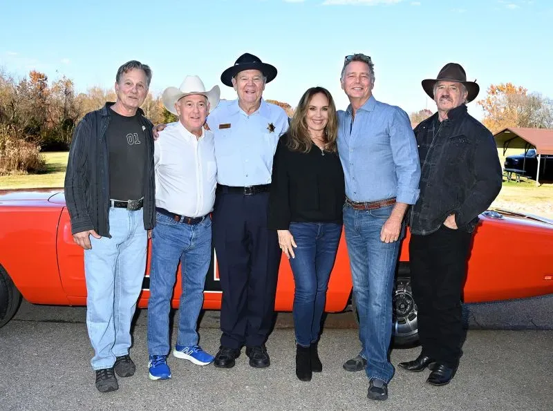 مجموعة من ممثلي مسلسل "Dukes of Hazzard" يقفون بجانب سيارة المسلسل الشهيرة، في لم شمل يبرز ذكرياتهم المشتركة.