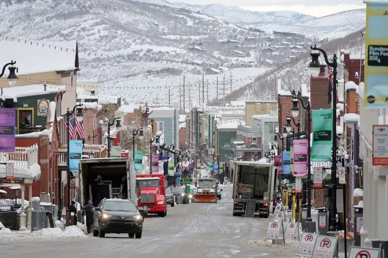 شارع مغطى بالثلوج في بارك سيتي، يوتا، مع شاحنات ومركبات تستعد لمهرجان صندانس السينمائي، الذي سينتقل إلى بولدر، كولورادو في 2027.