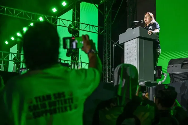 سارة دوتيرتي تتحدث أمام حشد من المؤيدين خلال تجمع انتخابي في الفلبين، مع خلفية مضيئة باللون الأخضر.