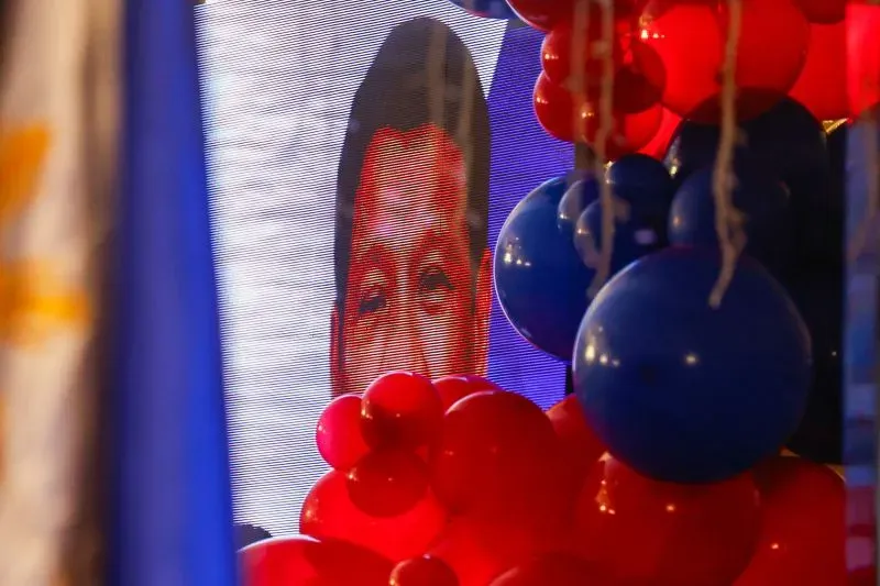 صورة لوجه الرئيس الفلبيني السابق رودريغو دوتيرتي على شاشة كبيرة، محاطاً بالبالونات الحمراء والزرقاء، خلال حملة انتخابية في دافاو.