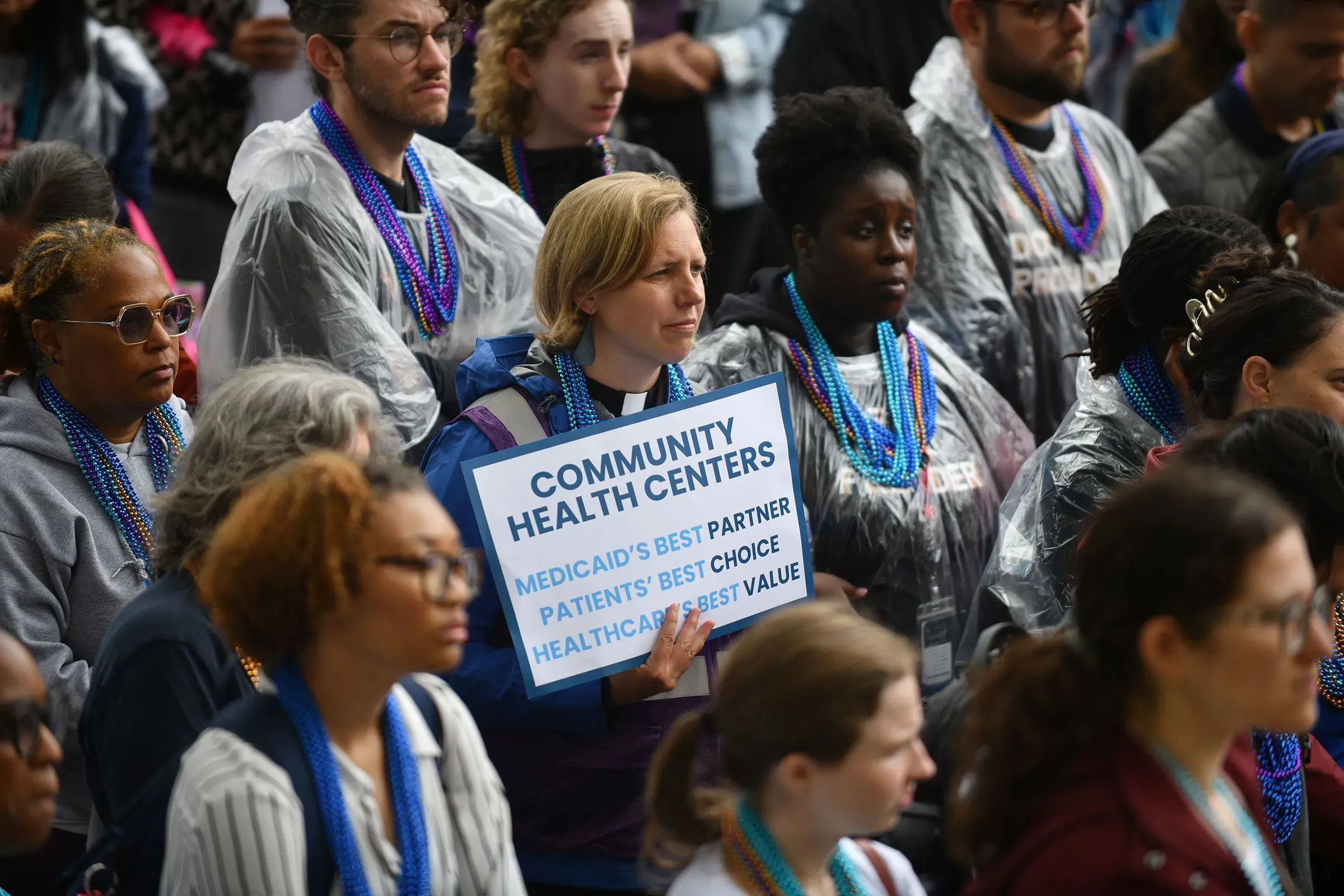 تجمع حاشد أمام مركز صحي، حيث تحمل امرأة لافتة مكتوب عليها "مراكز المجتمع: أفضل شريك لبرنامج ميديكيد، أفضل خيار للمرضى".