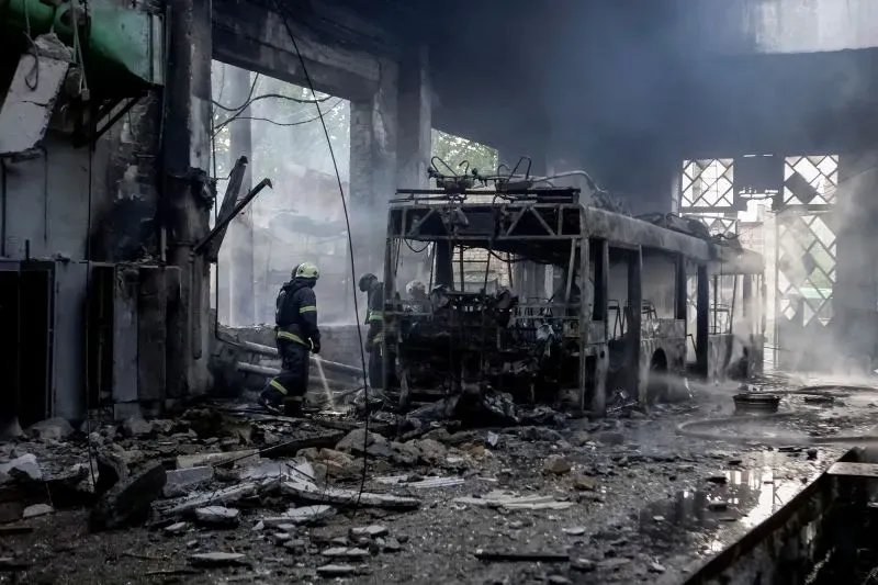 رجال الإطفاء يعملون على إخماد النيران في حافلة محترقة داخل مبنى مدمر، مما يعكس آثار الحرب في أوكرانيا.