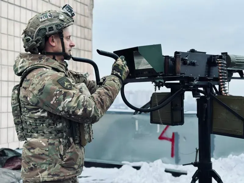 جندي أوكراني يرتدي زيًا عسكريًا، يراقب السماء من سطح مبنى في كييف، مستعدًا لمواجهة الطائرات بدون طيار في ظل تصاعد الهجمات الروسية.