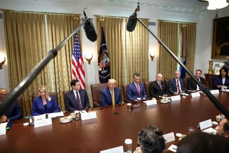 اجتماع لمجلس الوزراء الأمريكي حول دعم أوكرانيا، حيث يتواجد ترامب وسط مسؤولين، مع أعلام خلفهم وستائر ذهبية.