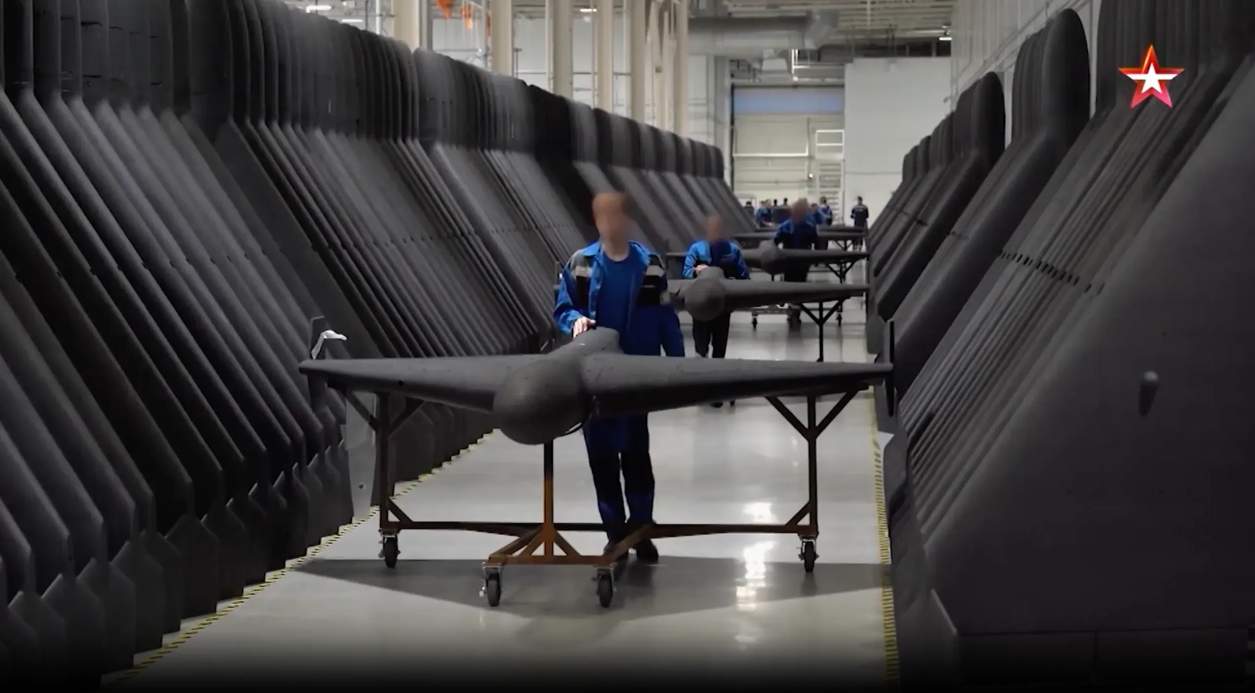 داخل مصنع "ألابوغا" للطائرات بدون طيار في روسيا، يظهر عمال وهم يقومون بتجميع الطائرات الهجومية ذات التصميم الإيراني، مع صفوف من الطائرات المميزة في الخلفية.