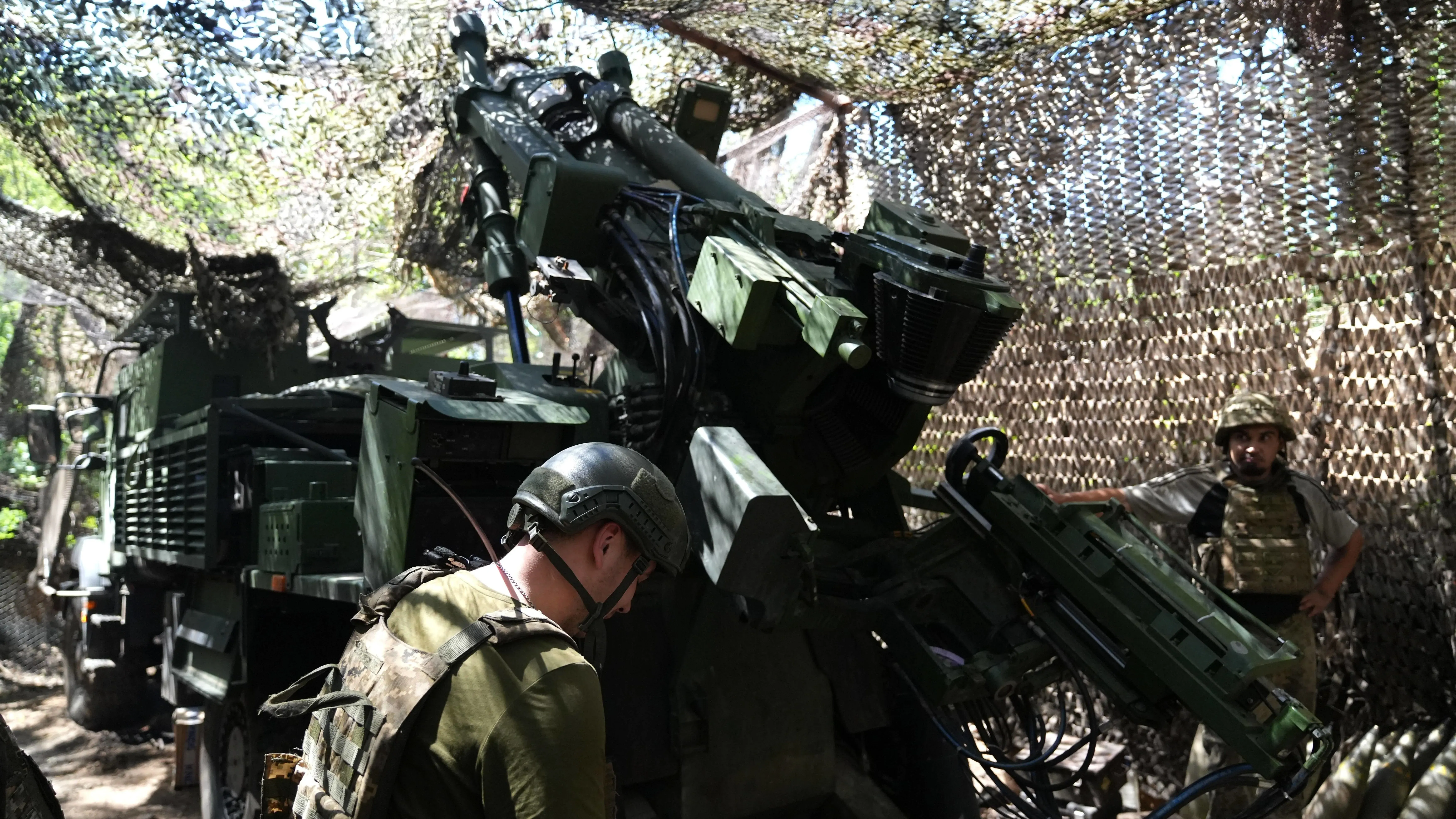 جنود أوكرانيون يعملون بالقرب من مدفعية متطورة تحت غطاء تمويهي، في سياق التصعيد العسكري في بوكروفسك.