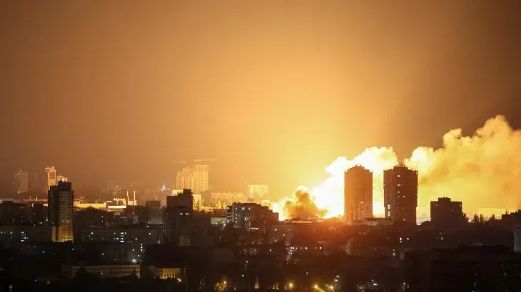 انفجار ضخم في سماء كييف ليلاً، مع تصاعد الدخان والحرائق في المباني، نتيجة لهجمات صاروخية وطائرات مسيرة.