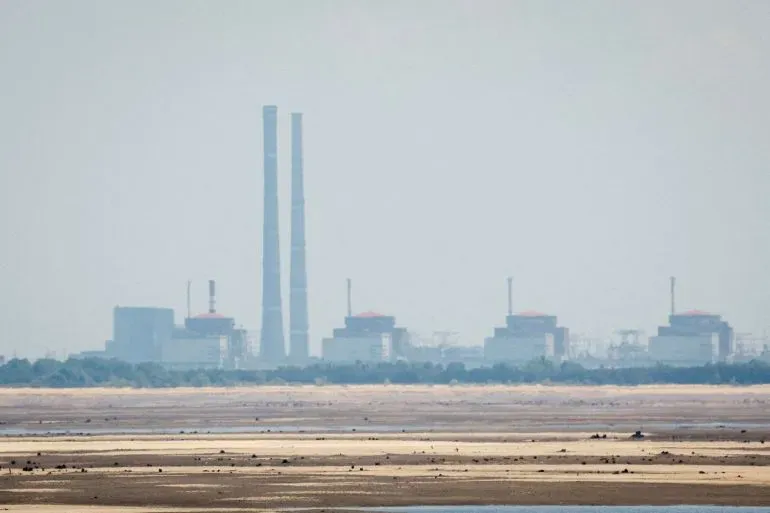 محطة زابوريجيزيا النووية في أوكرانيا، تظهر في الخلفية مع أبراجها العالية، وسط مشهد ضبابي يعكس التوترات الجارية.