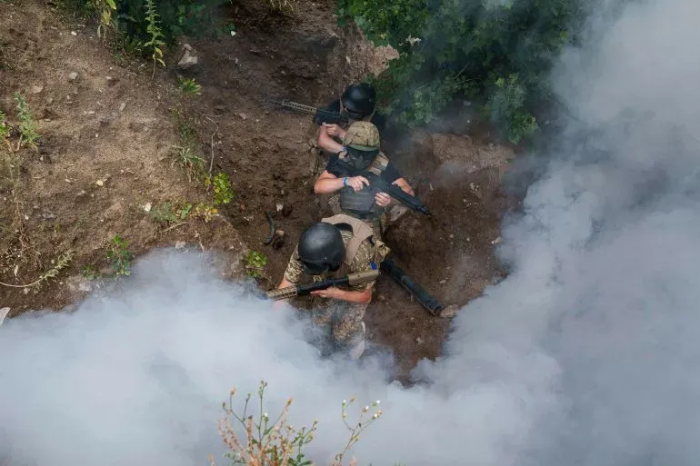 جنود أوكرانيون في موقع قتالي، يتخذون وضعية الدفاع وسط دخان كثيف، مما يعكس التوترات المستمرة في الحرب الأوكرانية.