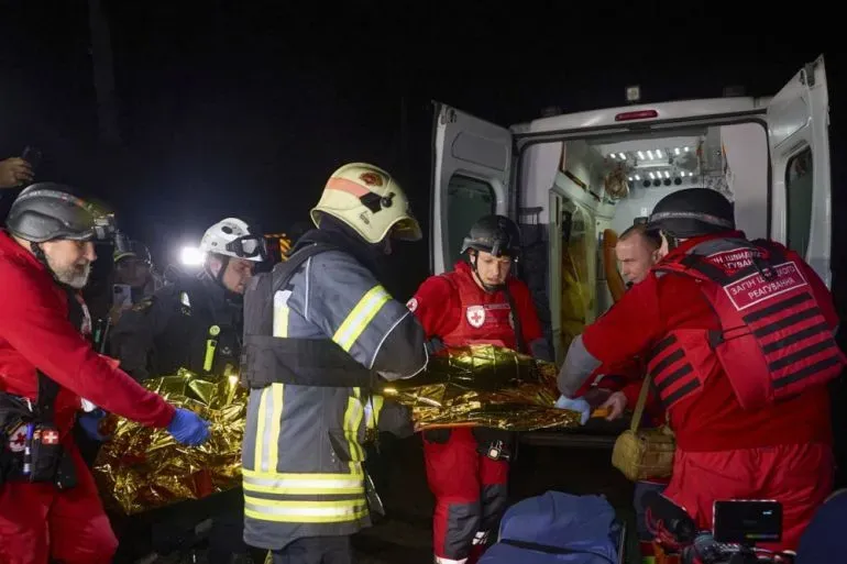 فرق الإنقاذ تعمل على نقل شخص مصاب إلى سيارة الإسعاف بعد هجوم بطائرات مسيرة في أوكرانيا، وسط أجواء مظلمة.