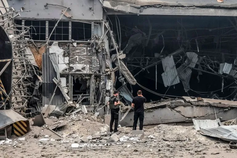 دمار واسع في مبنى صناعي في كييف بعد هجوم صاروخي روسي، مع وجود أشخاص يتفقدون الأضرار وسط أنقاض الحطام.