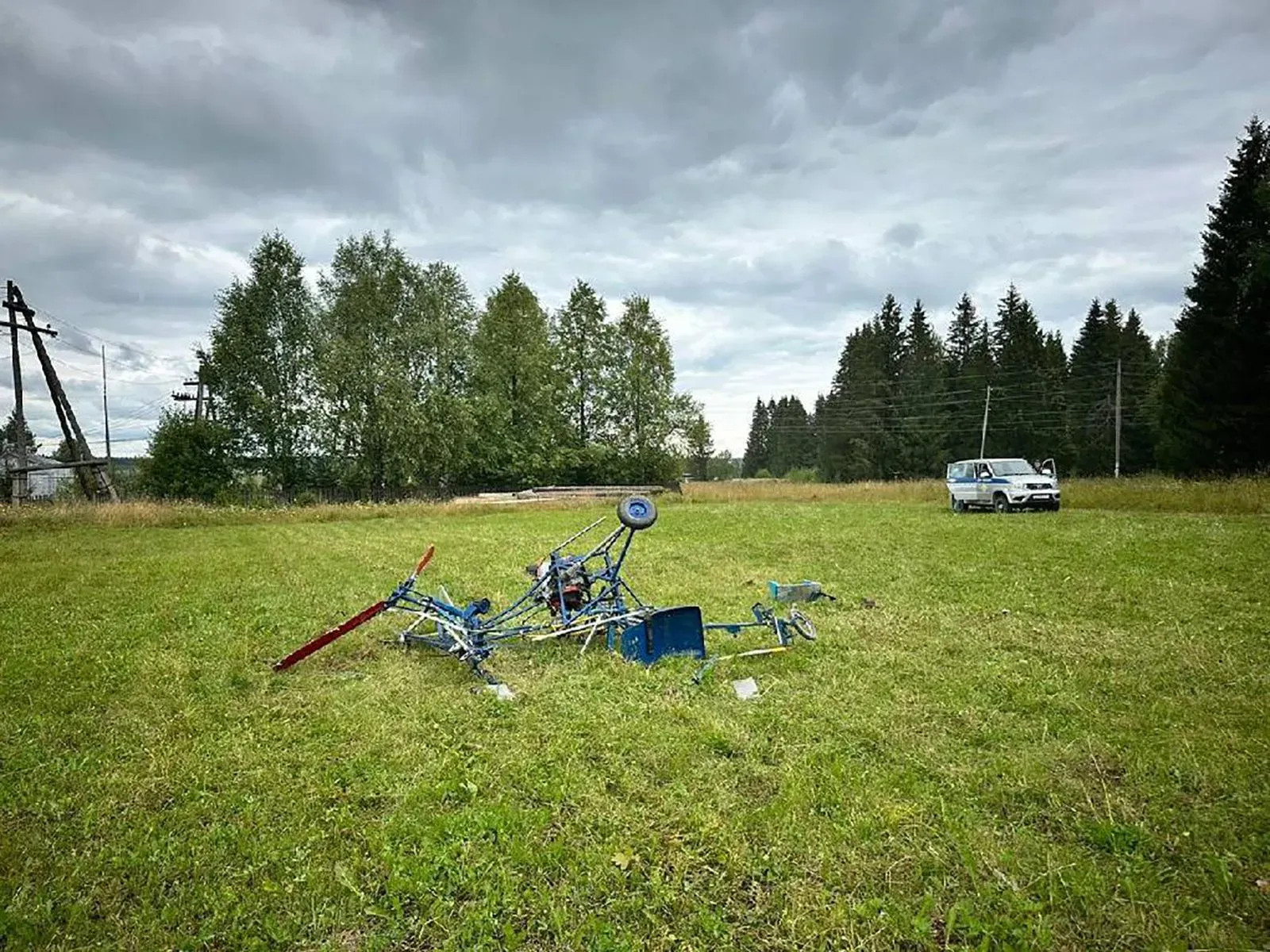 حطام مروحية محلية الصنع في حقل، بعد محاولة فاشلة للإقلاع، مع وجود سيارة في الخلفية، تعكس شغف المخترع فلاديمير ترابيزنيكوف.