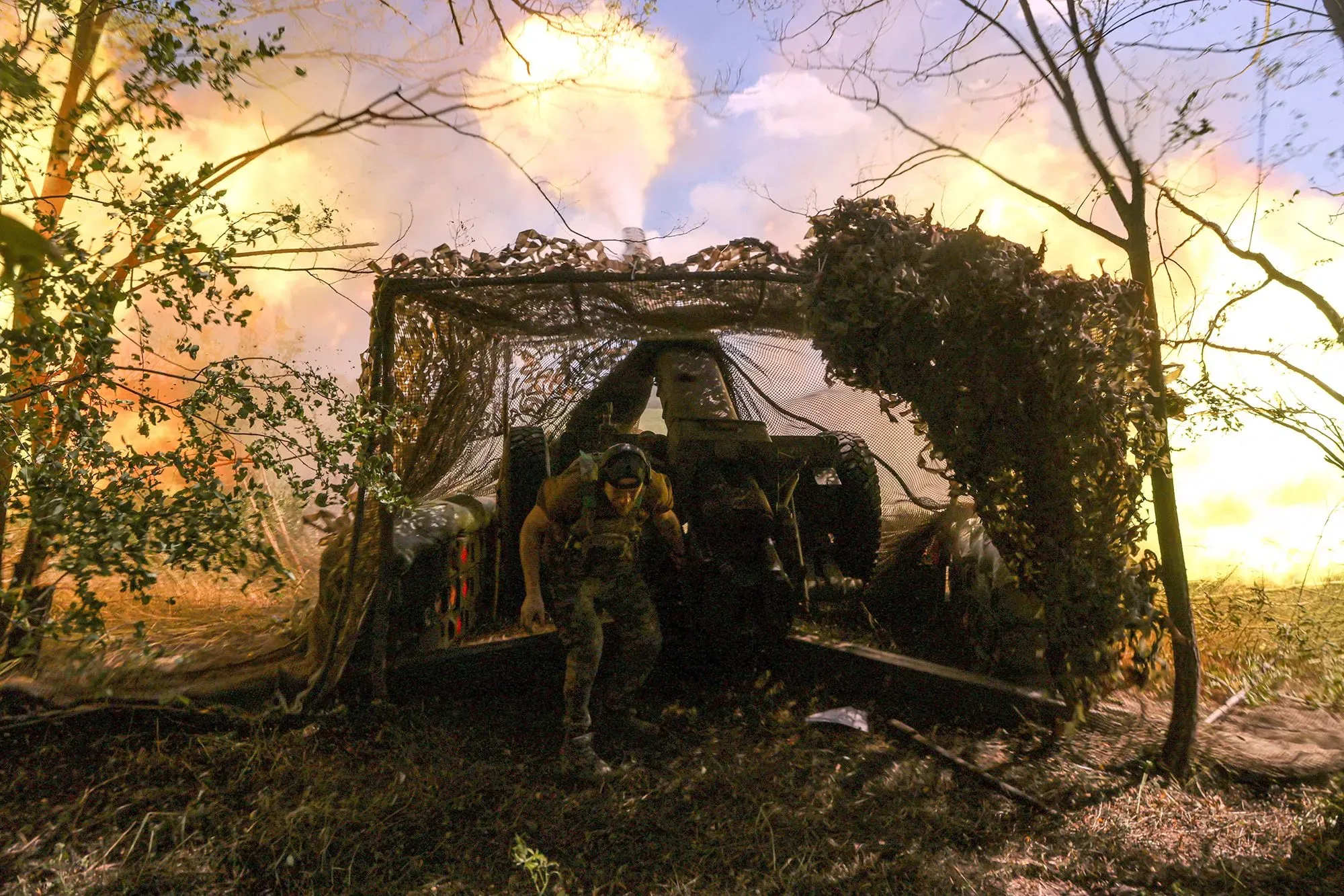 صورة لجندي أوكراني يتحرك من خلف ساتر في منطقة قتال مشتعلة، حيث تتصاعد النيران والدخان في الخلفية، مما يعكس تصاعد التوترات العسكرية في دونيتسك.