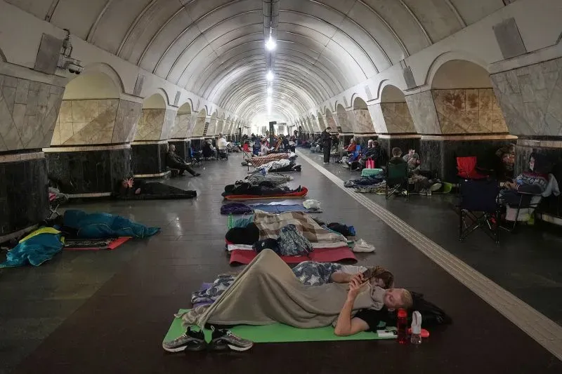 تظهر الصورة مجموعة من الأشخاص يستريحون في محطة مترو تحت الأرض في كييف، حيث يلجأون إلى الملاجئ هربًا من الهجمات الجوية الروسية.