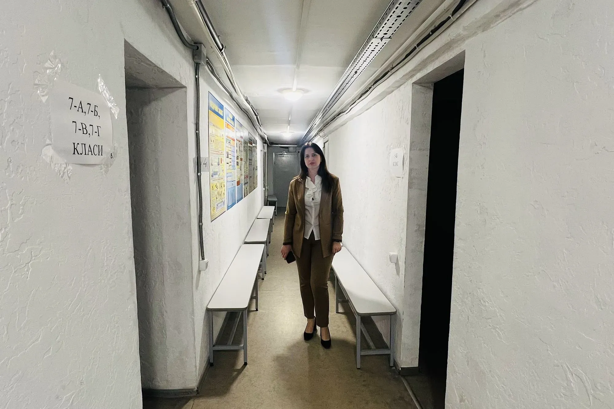 ممر في مدرسة كييف حيث تتواجد طلاب الصف الأول، مع لافتات تشير إلى فصول دراسية، وسط إجراءات السلامة من الغارات الجوية.