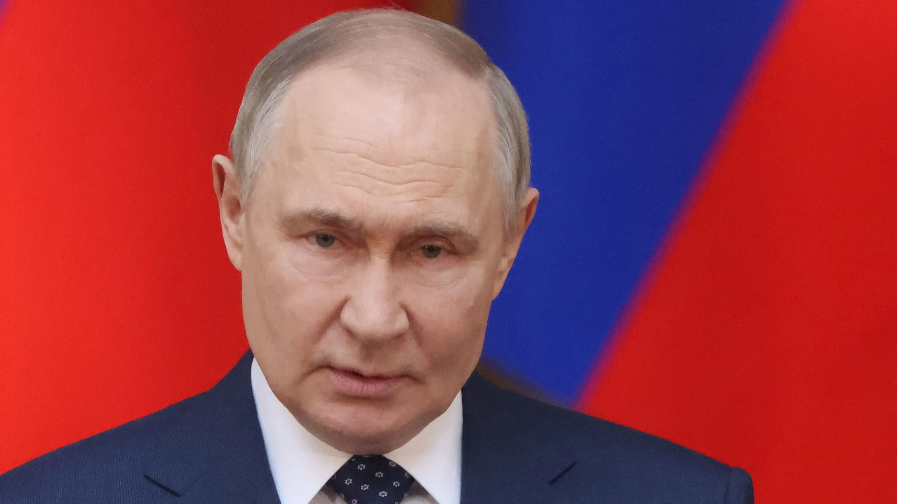 تصريح للرئيس الروسي فلاديمير بوتين أثناء حديثه عن الحرب في أوكرانيا، مع خلفية تتضمن العلمين الروسي والأوكراني.