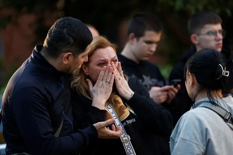 امرأة تبكي بينما يتجمع حولها آخرون في مشهد يعكس التأثير العاطفي للصراع في أوكرانيا، مع التركيز على الألم والخسارة.