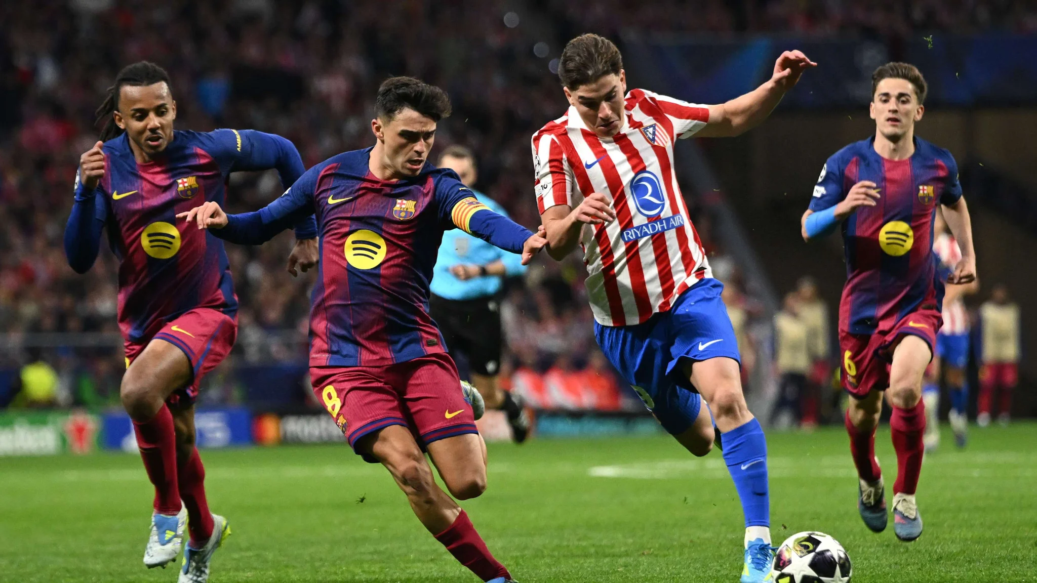 لاعب أتلتيكو مدريد خوليان ألفاريز يحاول السيطرة على الكرة وسط ضغط من لاعبي برشلونة خلال مباراة في الدوري الإسباني.