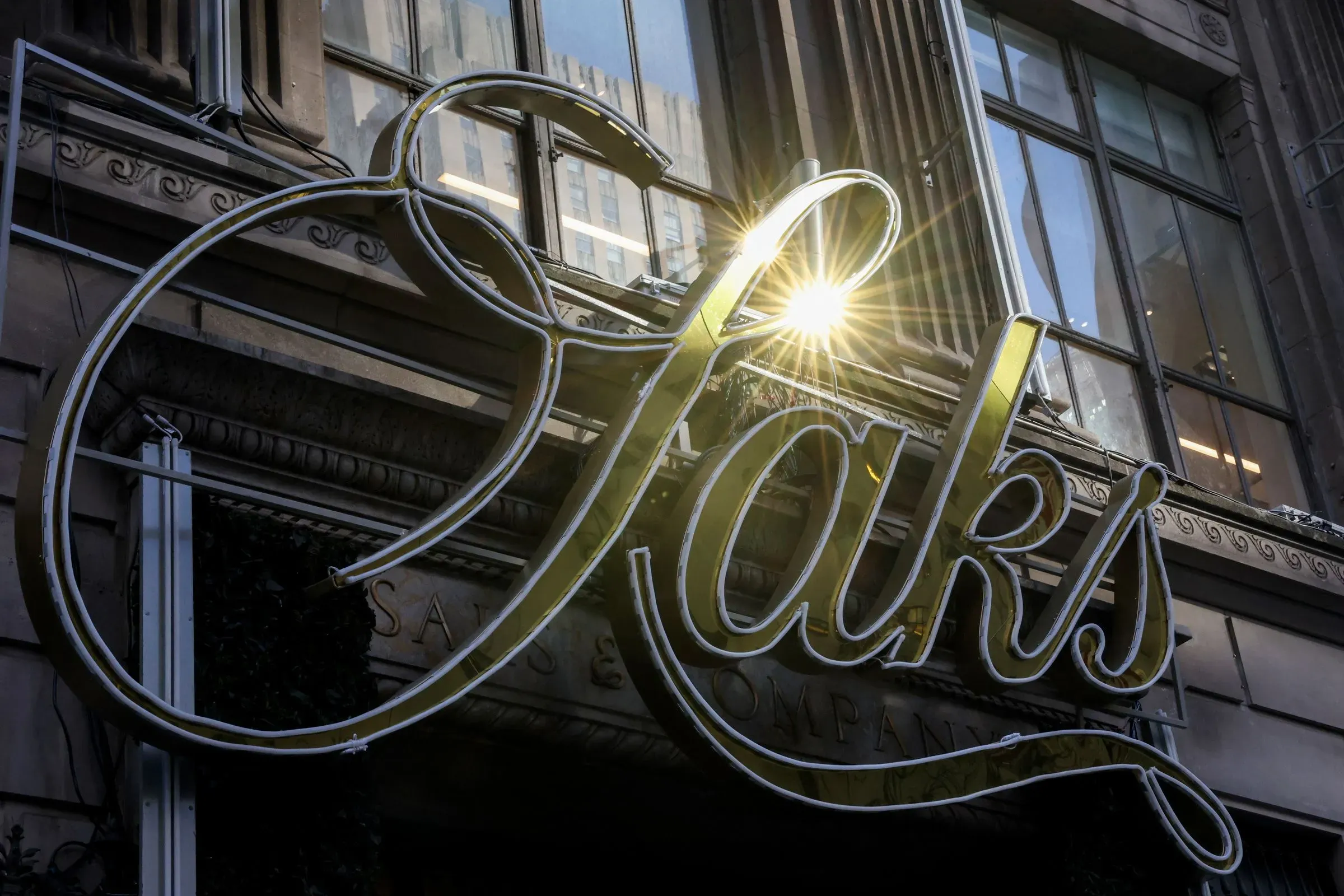 لافتة متلألئة لمتجر ساكس، تعكس الضوء، تشير إلى التحول في استراتيجية الشركة نحو التركيز على المتاجر الفاخرة بعد إغلاق مواقع أوف فيفث.