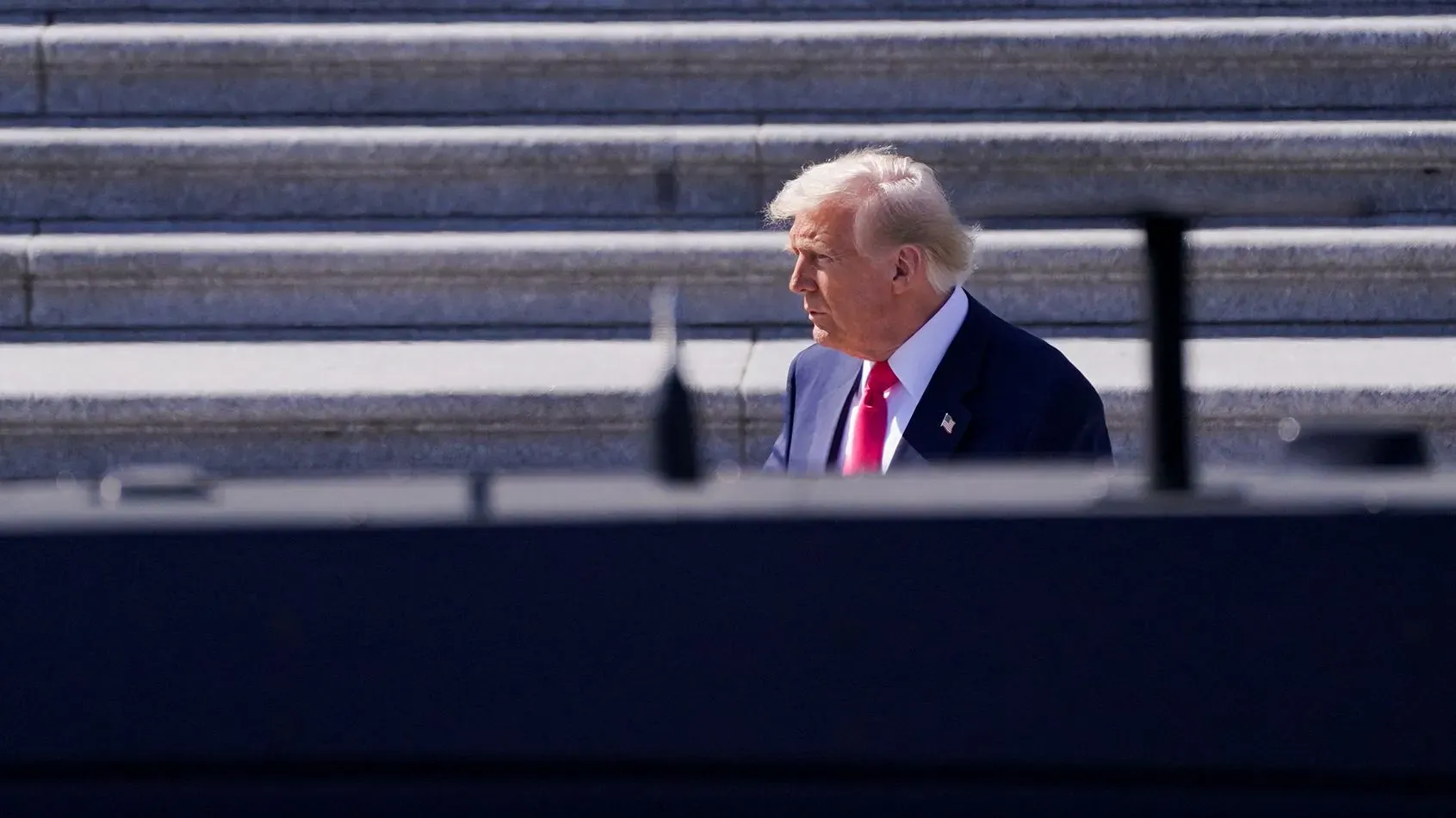 دونالد ترامب يسير بجانب درجات مبنى الكابيتول، مع التركيز على دوره في تمرير مشروع قانون الإنفاق وسط تحديات سياسية.