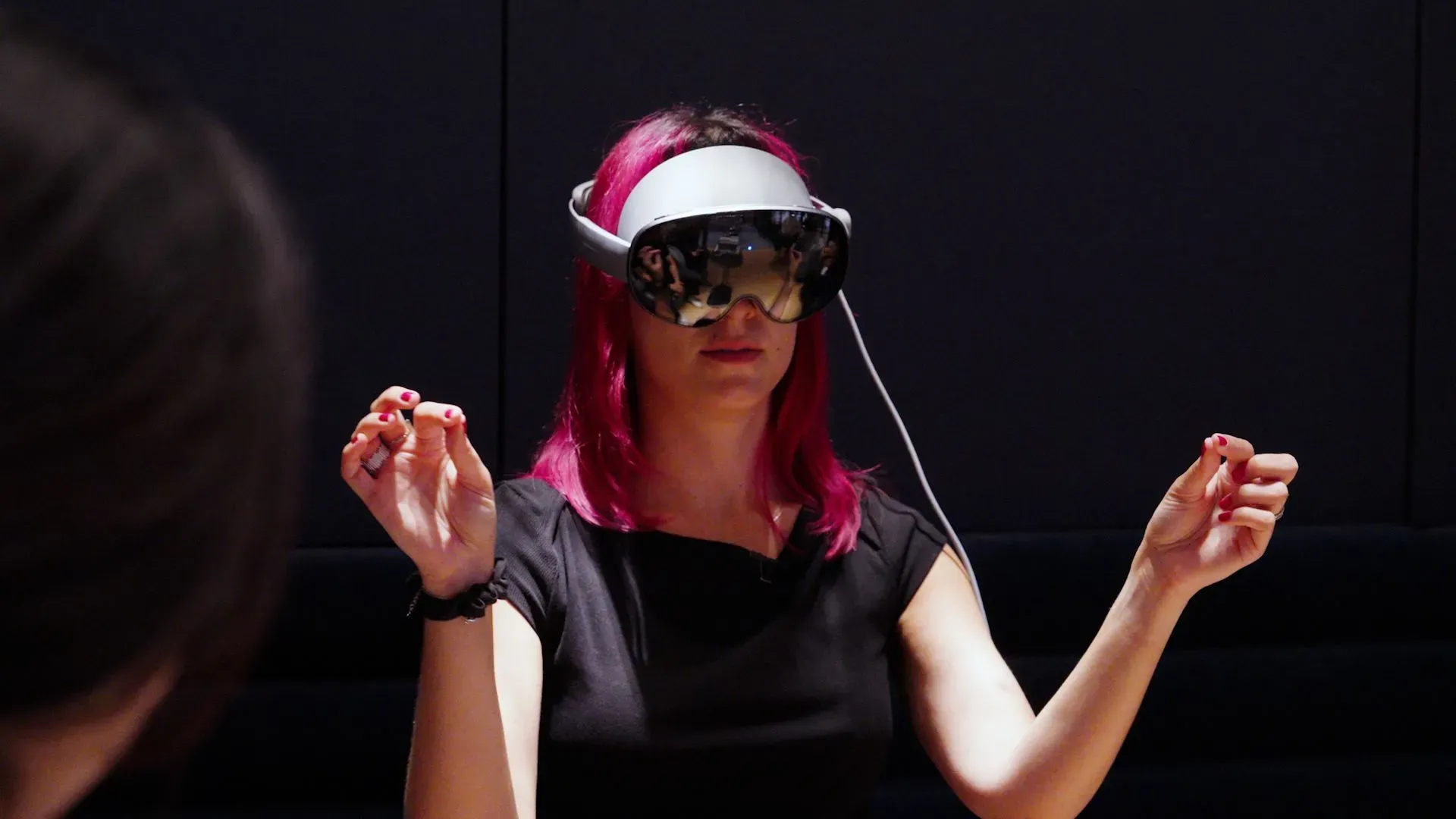 امرأة ترتدي سماعة Galaxy XR الجديدة من سامسونج، تستخدم إيماءات اليد للتفاعل مع التطبيقات الافتراضية في بيئة تكنولوجية متقدمة.