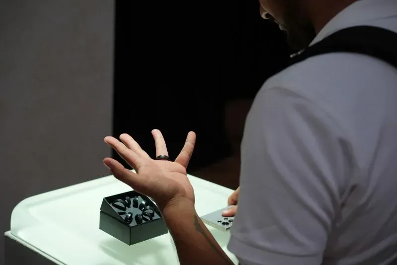 رجل يستعرض جهازًا صحيًا مبتكرًا على طاولة عرض، مع التركيز على يده التي ترتدي حلقة ذكية.