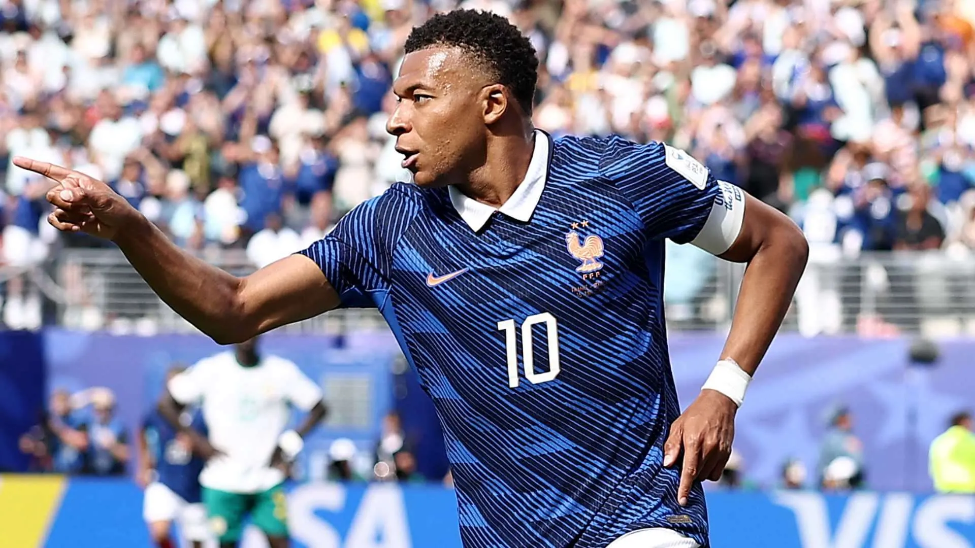 كيليان مبابي بقميص منتخب فرنسا رقم 10 يحتفل بهدف خلال مباراة في كأس العالم 2026، مع التركيز على قيادته للفريق ونقاش حول اعتراف بلاده به.