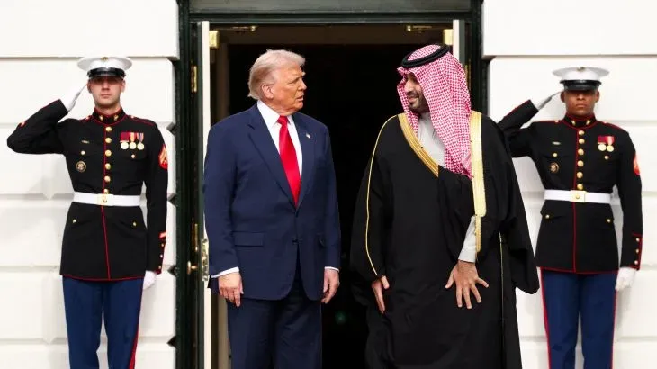 ترامب وولي العهد السعودي محمد بن سلمان يتحدثان أمام البيت الأبيض، مع حراس الأمن في الخلفية، خلال زيارة رسمية لتعزيز التعاون العسكري.