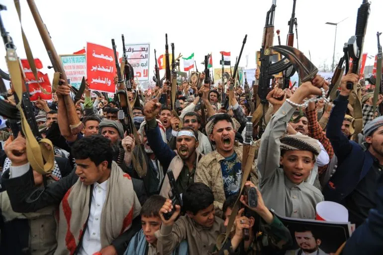 مسلحون حوثيون يرفعون أسلحتهم ويهتفون خلال مظاهرة في اليمن وسط تصاعد النزاع مع السعودية.