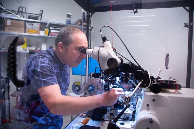 عالم يستخدم مجهرًا متخصصًا لدراسة نشاط دماغ فأر، مع التركيز على تفاصيل دقيقة لفهم الخلايا العصبية في القشرة البصرية.