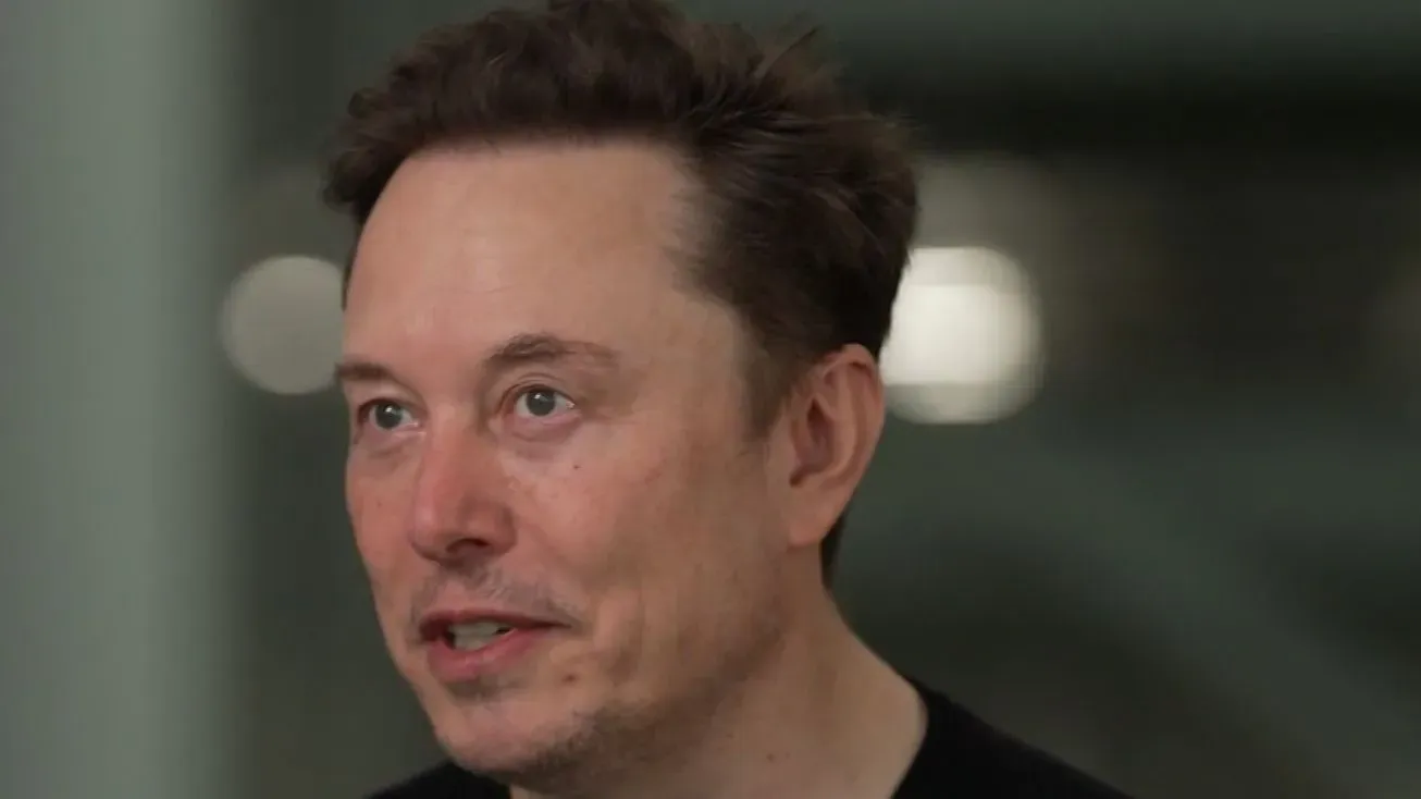 إيلون ماسك يتحدث في مؤتمر، مع تعبير جاد، في سياق مناقشة تأثيره على الميزانية الفيدرالية والإنفاق الحكومي.