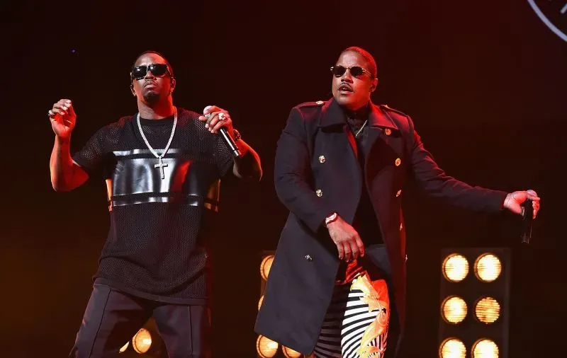 مغني الراب شون "ديدي" كومبس ومغني آخر يؤدون معًا على المسرح، مع أضواء ساطعة خلفهم، في عرض موسيقي مميز.