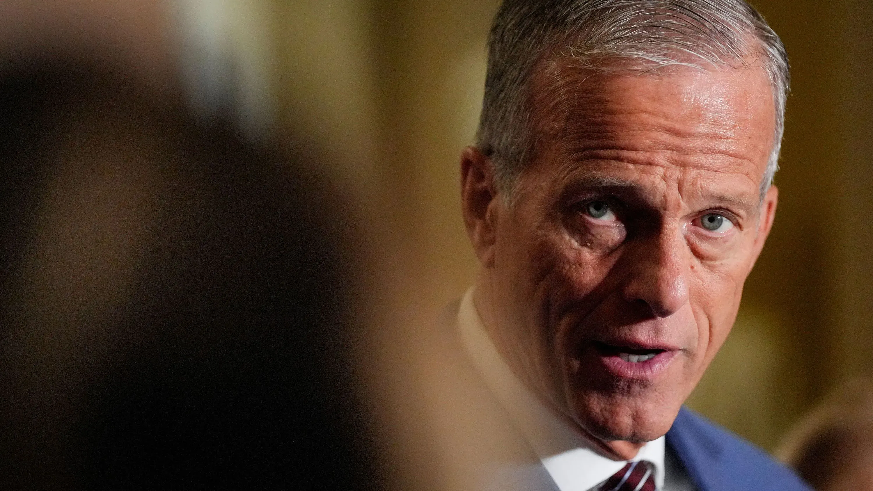 سناتور يتحدث للصحفيين في مبنى الكابيتول، مع التركيز على قضايا الميزانية والمساعدات الخارجية، وسط أجواء مشحونة.