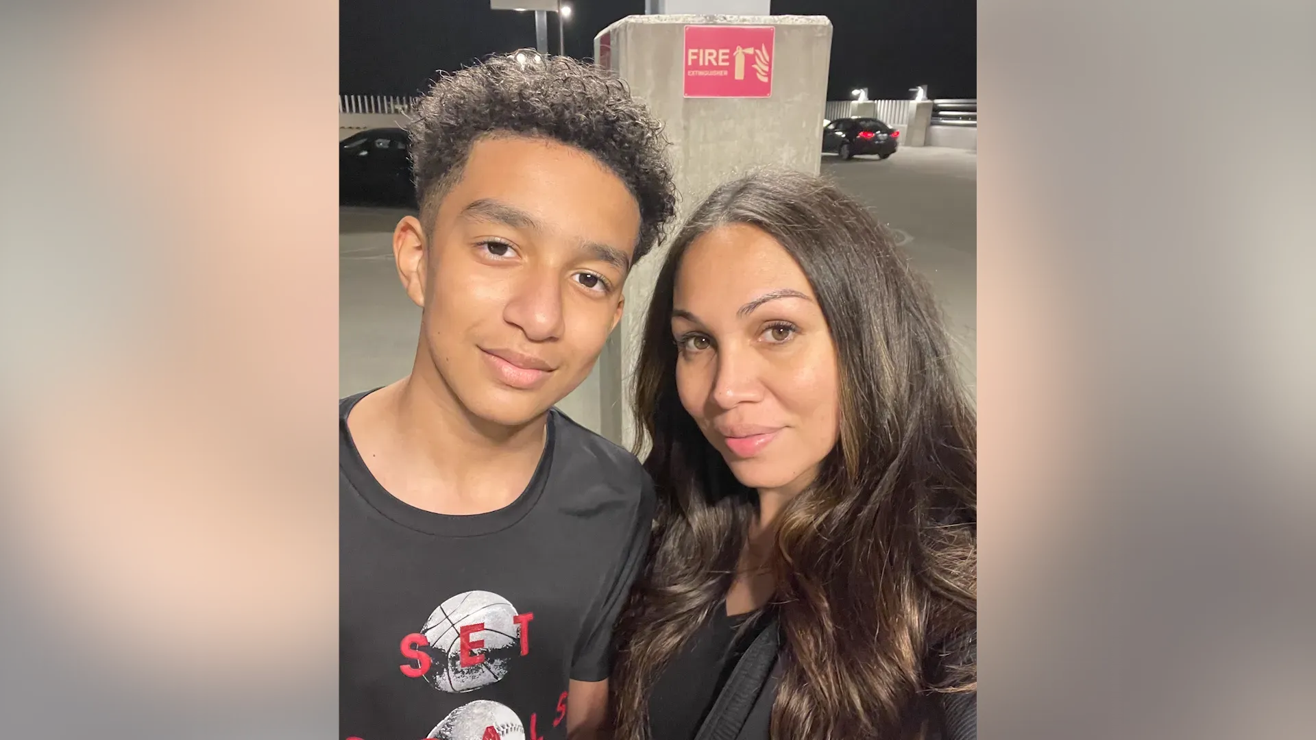 صورة لأم وابنها المراهق، حيث يبدو كلاهما مبتسمين في مكان عام. تعكس الصورة العلاقة الأسرية في سياق المخاوف من تأثيرات الذكاء الاصطناعي على الشباب.