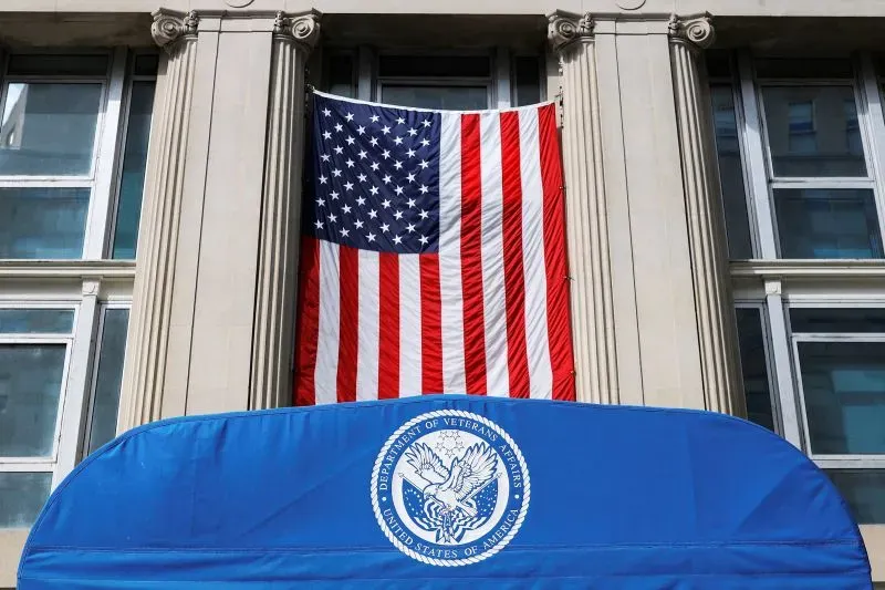 علم الولايات المتحدة الأمريكية مع شعار وزارة شؤون المحاربين القدامى، يرمز إلى التحديات التي تواجه الرعاية الصحية للمحاربين القدامى.