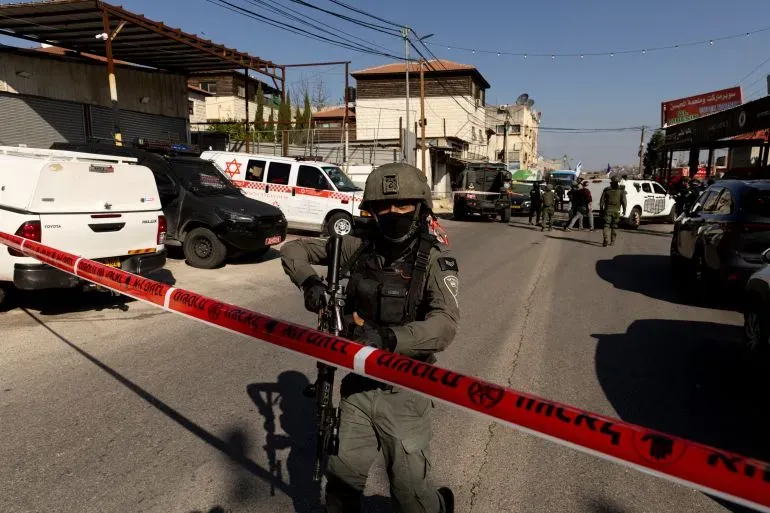 عناصر أمنية إسرائيلية تحمل أسلحة وتؤمن منطقة محاطة بشريط تحذيري، في سياق تصاعد العنف في الضفة الغربية.