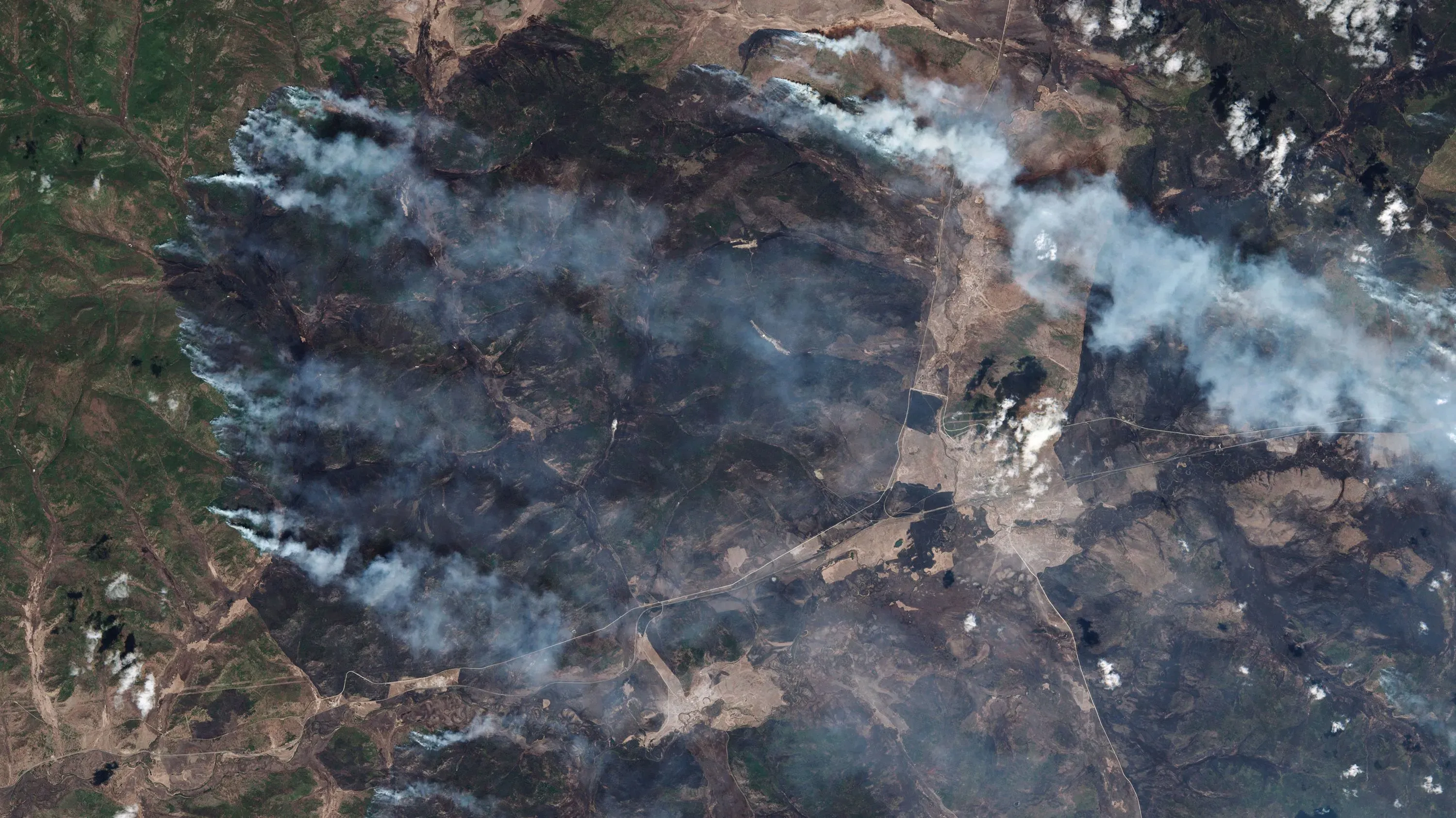 حرائق غابات واسعة في سيبيريا، مع تصاعد الدخان الذي يغطي الأراضي المحترقة، مما يعكس تأثير تغير المناخ على البيئة.