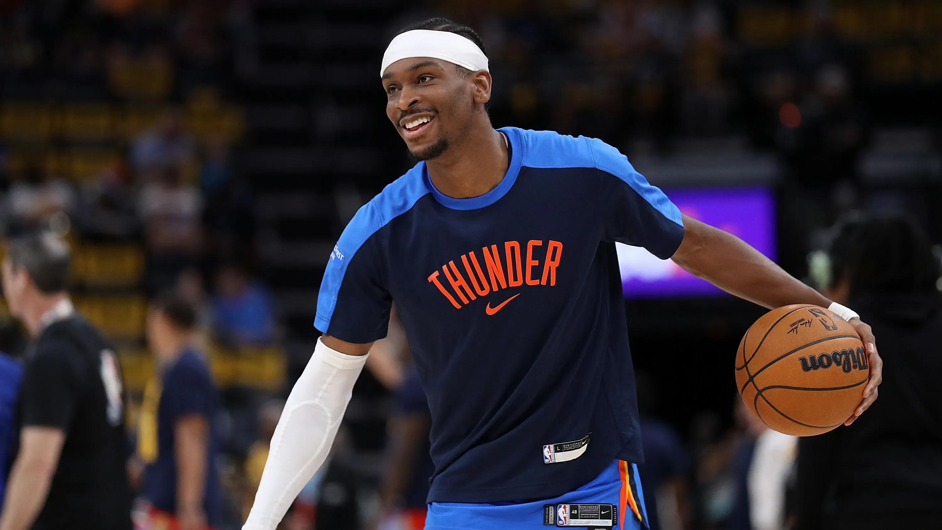 شاي جيلجوس-أليكساندر يرتدي زي فريق أوكلاهوما سيتي ثاندر، مبتسمًا أثناء التدريب، مما يعكس نجاحه في الدوري الأمريكي للمحترفين.