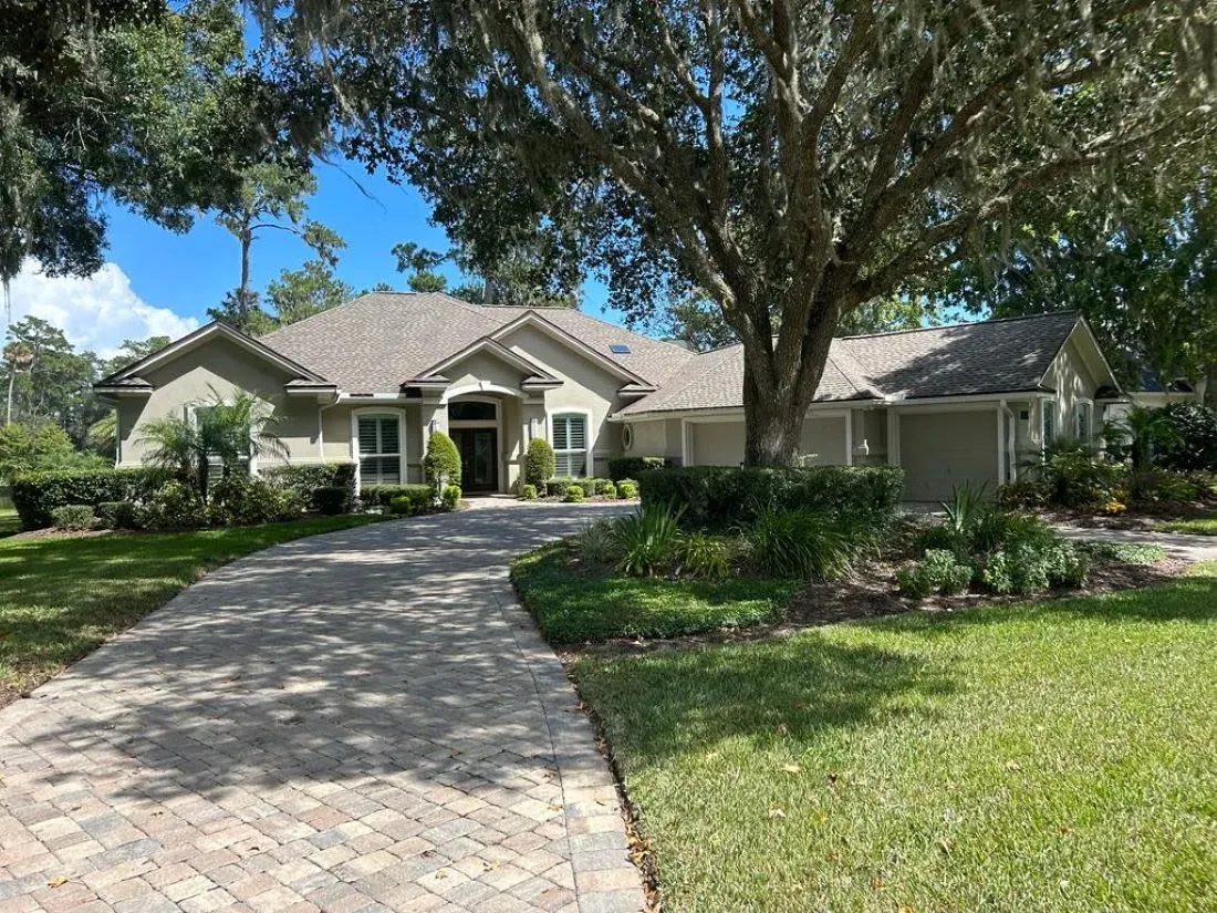 منزل عائلة بورشيل في نادي ساوجراس بلايرز، محاط بالأشجار والحدائق الخضراء، مع مدخل واسع وممر مرصوف.