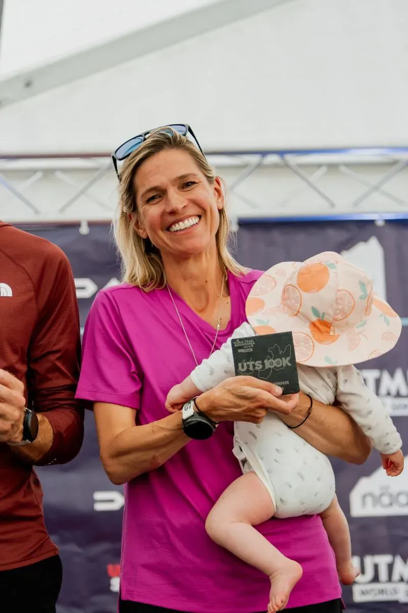 ستيفاني كيس تحمل ابنتها بيبر بعد فوزها في سباق الجري لمسافة 100 كيلومتر، معبرة عن فرحتها بإنجازها كأم وعداءة.