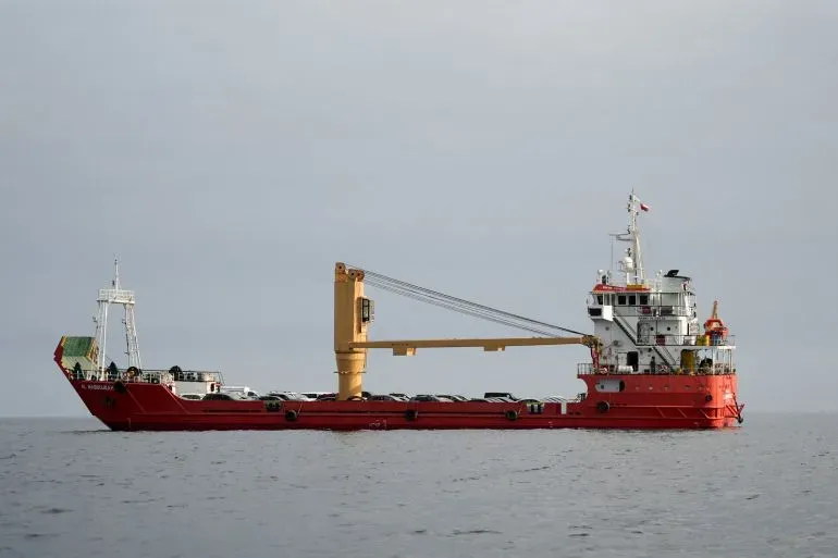 سفينة شحن حمراء تبحر في البحر، تمثل حركة التجارة البحرية في ظل التوترات حول مضيق هرمز وفتح الممر أمام السفن التجارية.