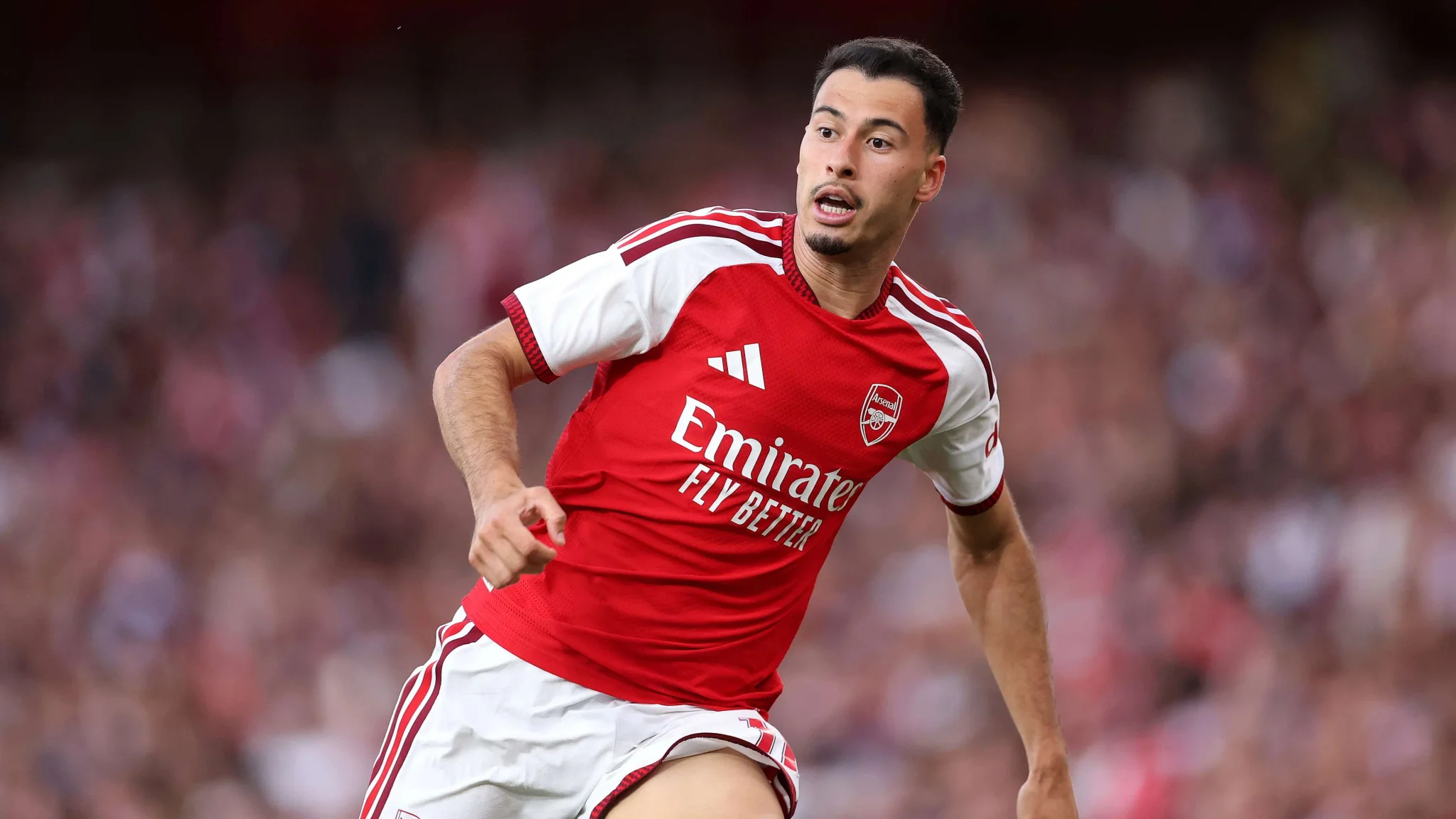 لاعب أرسنال في منتصف المباراة يرتدي الزي الأحمر والأبيض، مع تركيز على تحركاته في ملعب كرة القدم خلال موسم الانتقالات.