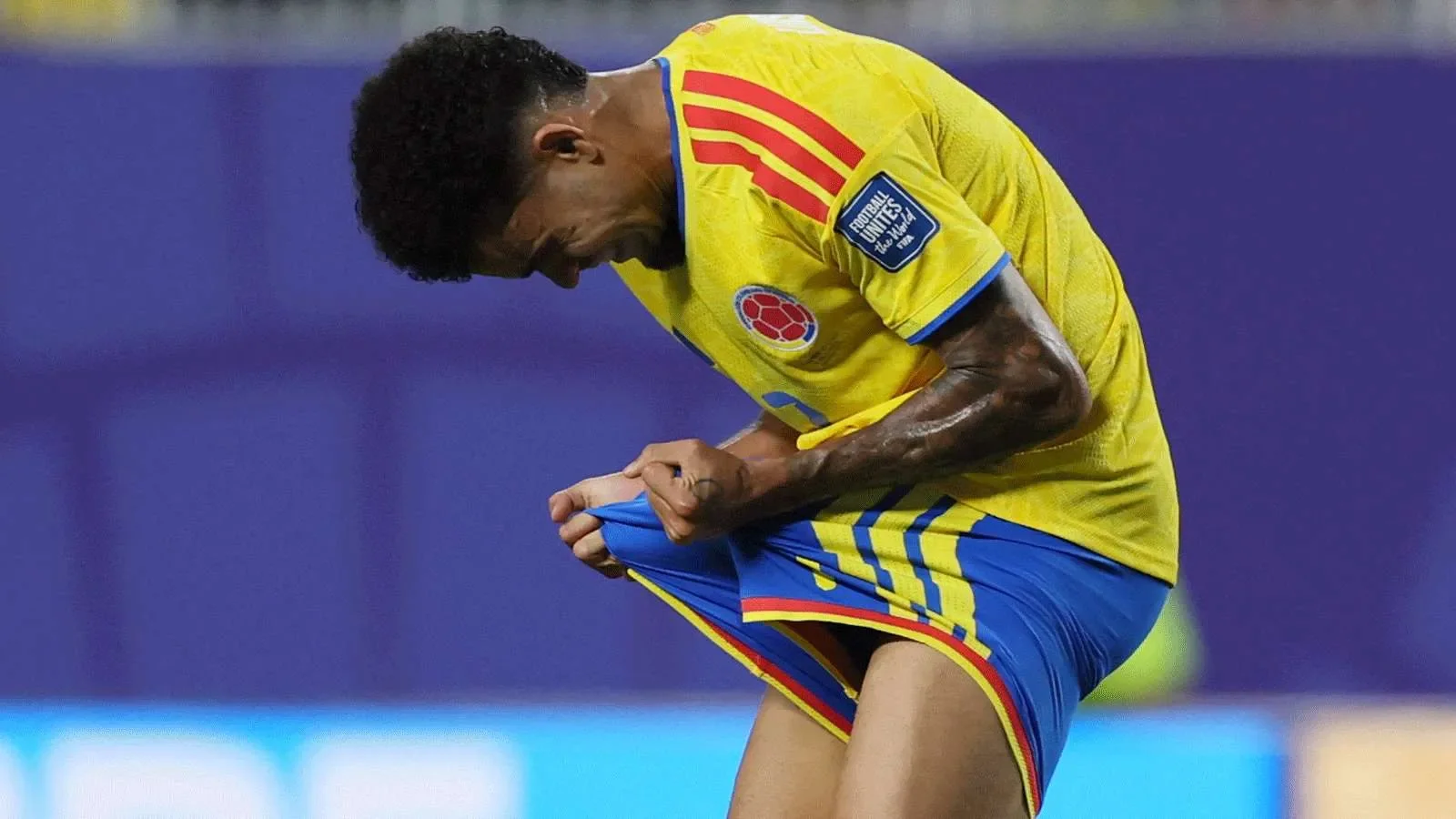 لاعب كولومبي يرتدي زي المنتخب يمسك قميصه بإحباط بعد خسارة فريقه أمام سويسرا في مباراة دور الستة عشر.
