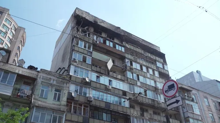 مبنى سكني في كييف يظهر آثار الدمار، مع شرفات محطمة ونوافذ مكسورة، مما يعكس تأثير الحرب المستمرة على المدنيين.