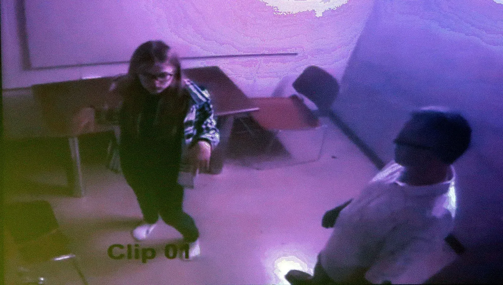 امرأة شابة ترتدي نظارات وتستعد للتحدث مع شخص بالغ في غرفة مغلقة، تعكس لحظة من التوتر في سياق قضيتها الشهيرة.