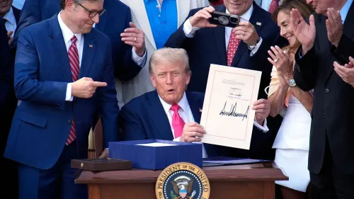 الرئيس دونالد ترامب يوقع قانون التخفيضات الضريبية والإنفاق الشامل، محاطًا بمسؤولين ومؤيدين، مما يشير إلى تغييرات كبيرة في التغطية الصحية.