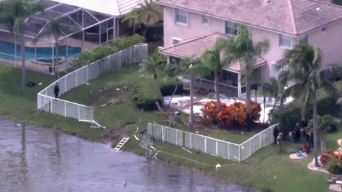 تحطم طائرة صغيرة في بركة بحي سكني في فورت لودرديل، مما أسفر عن مقتل شخصين، مع وجود حطام بالقرب من السياج المكسور.