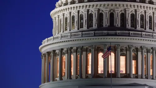 قبة مبنى الكابيتول الأمريكي تضيء في الليل، مع العلم الأمريكي يرفرف في المقدمة، تعكس الوضع السياسي الحالي للحزب الديمقراطي.